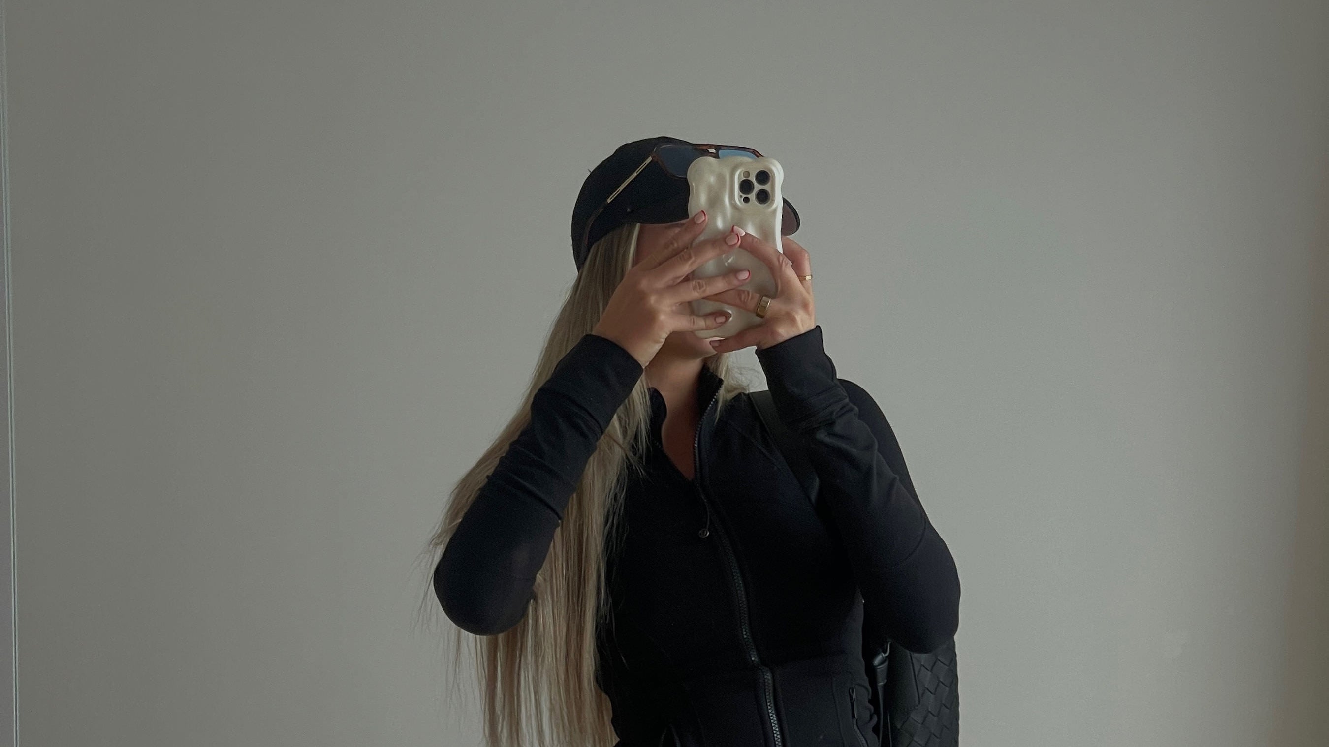 Person wearing a black outfit with a vest against a plain background